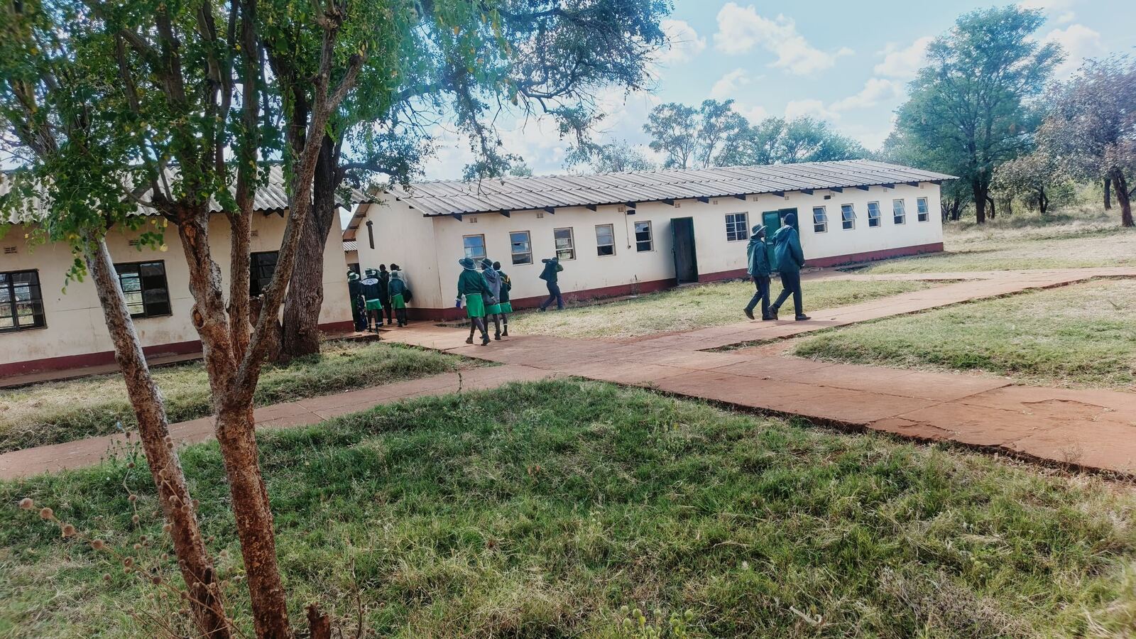 Learners walking between classroom blocks at Siganda Secondary School