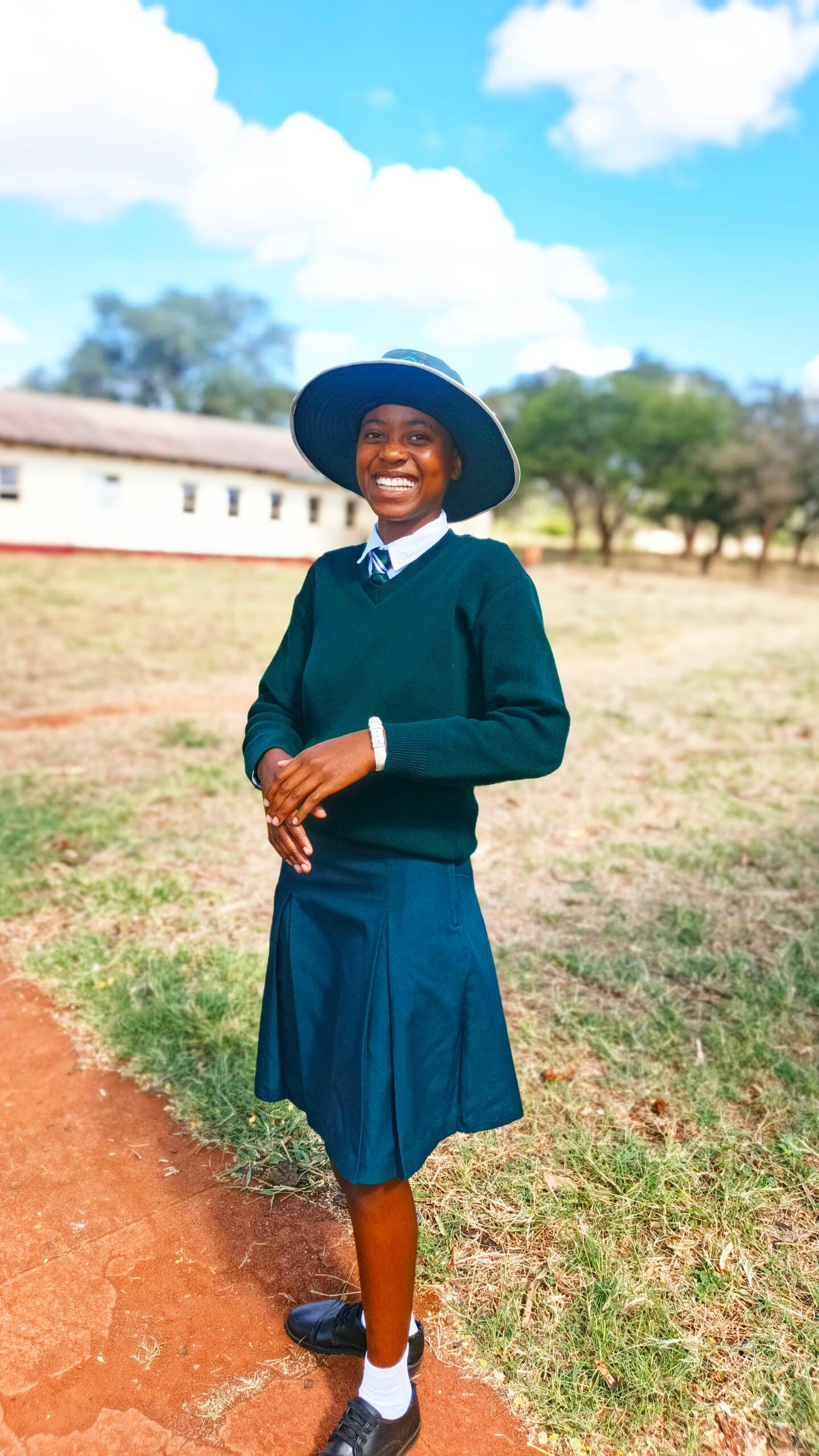 Female learner in school uniform and sun hat